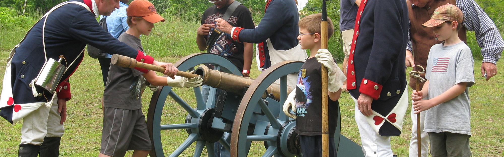Patriot re-enactors show school age children how to fire a canon