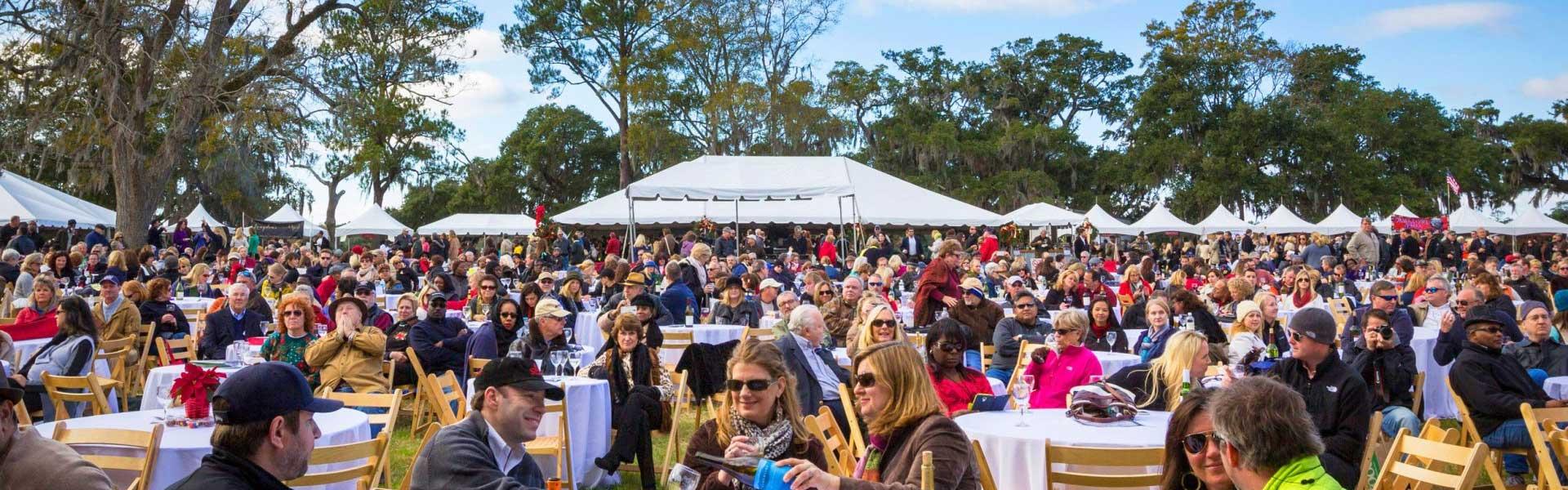 a photo of a crowd of people enjoying wine outside under tents
