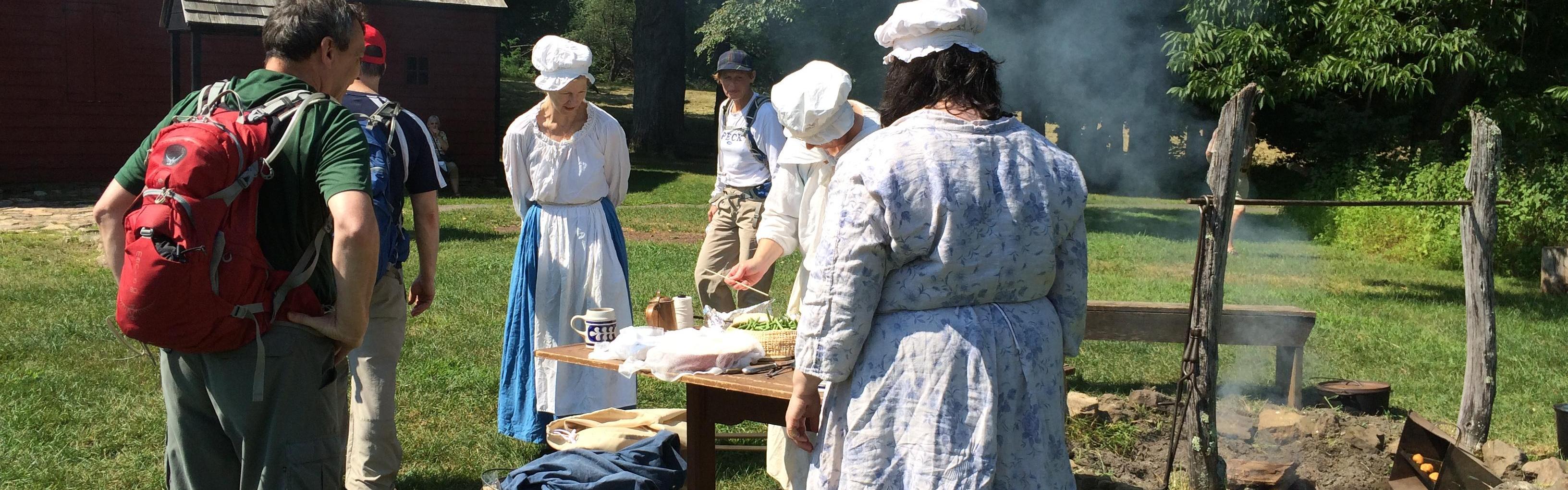 Women in colonial clothing giving a demonstration to tourists.