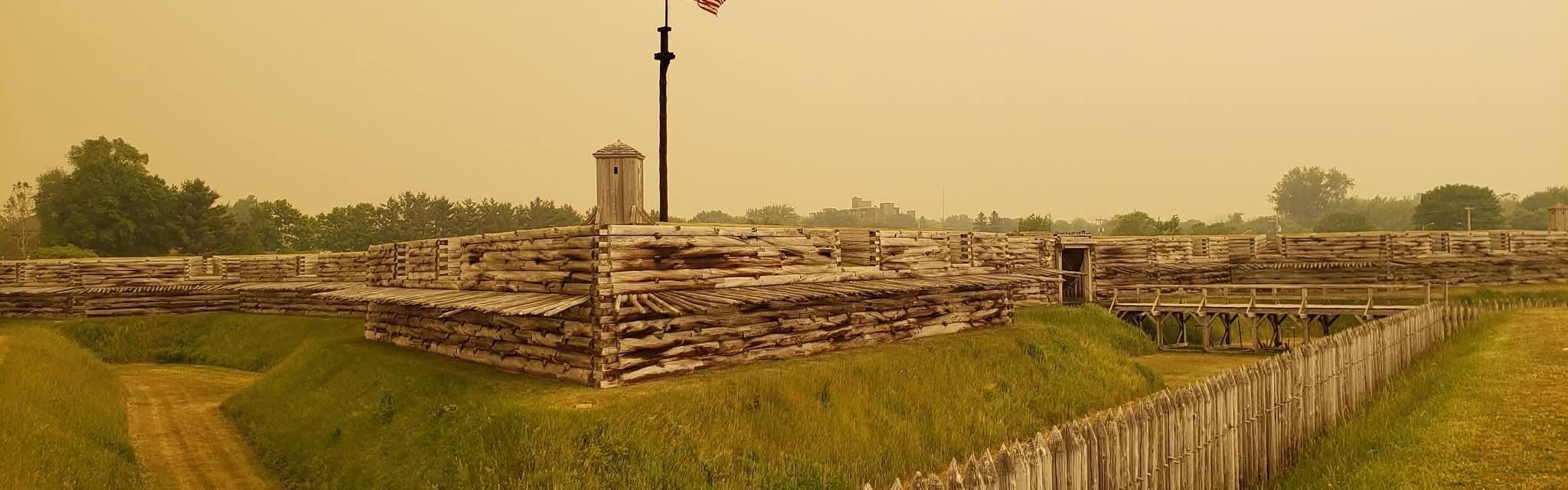 An eerie yellow, hazy sky surrounds the wooden fort. It makes it look strange.