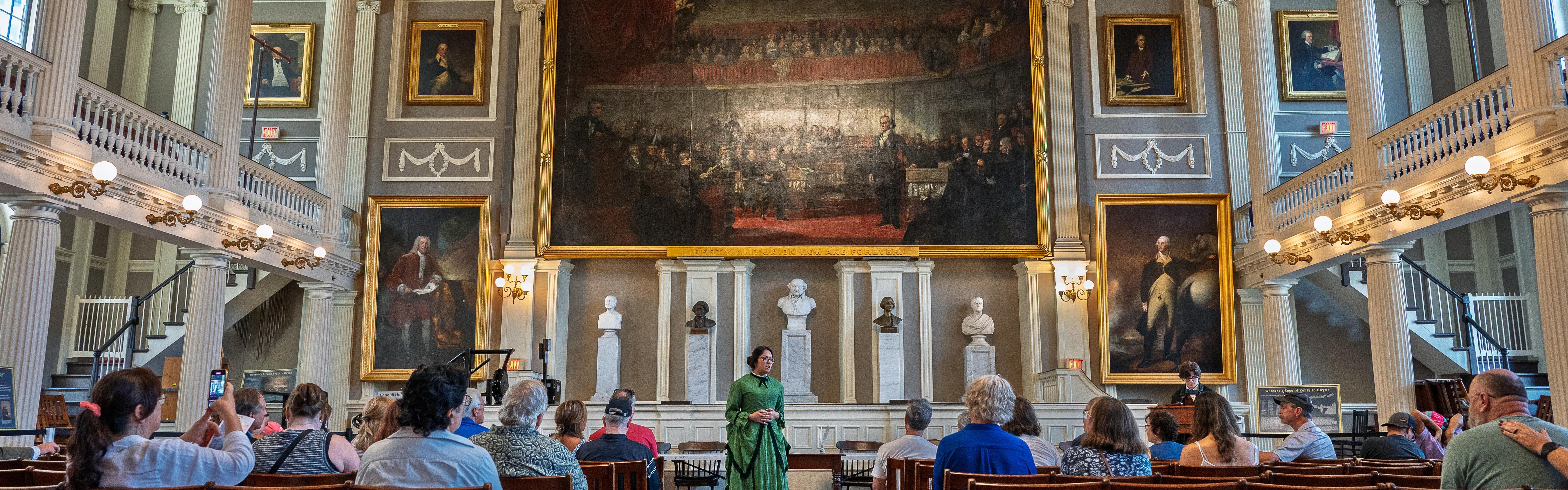 Photo of Rangers dressed in historic clothing in a large room with lots of people watching