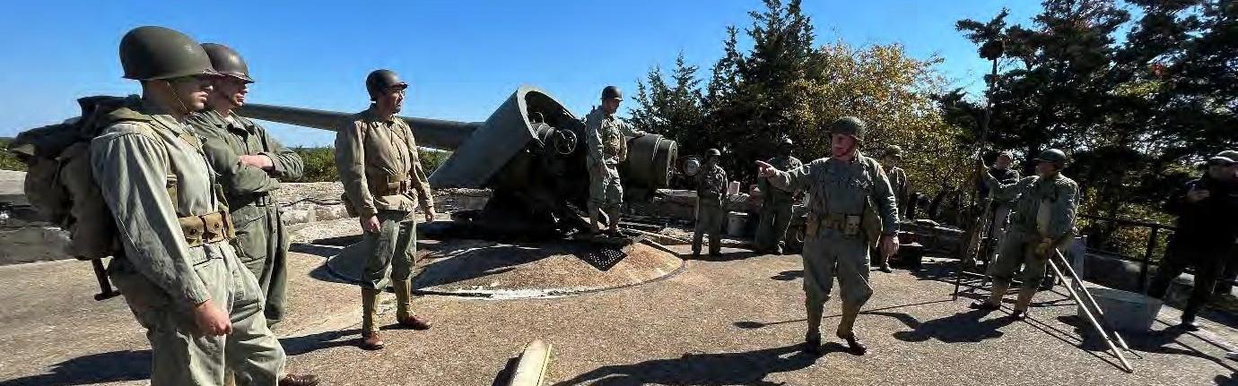 Group of men in uniform beside a historic cannon.