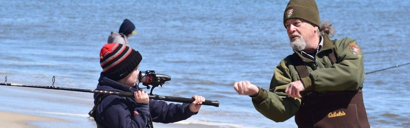Ranger teaching child how to use fishing equipment