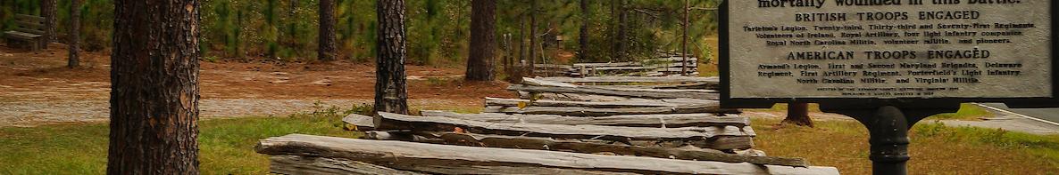 Image of a split rail fence along the side of a road with a historical marker sign reading Battle of Camede