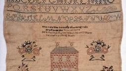 Piece of embroidery with letters, numbers, and house