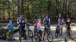 Ten men and boy cyclists pose with their road bikes, wearing helmets and smiling