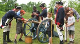 Patriot re-enactors show school age children how to fire a canon