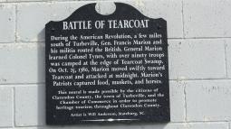 Black sign on a white brick wall with the title of Battle of Tearcoat