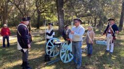 Image of tourists learning to fire a canon from costumed re-enactors