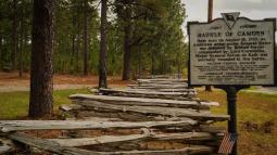 Image of a split rail fence along the side of a road with a historical marker sign reading Battle of Camden