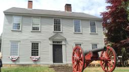 Facade of the two story Nathanael Greene homestead with an artillery piece in the foreground