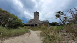 Historic shingle covered building among beach vegetation
