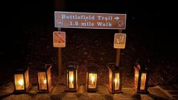 6 lanterns are shining in the night in front of a sign that says "Battlefiield Trail 1.5mi walk"