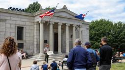 A ranger stands in front of the Bunker Hill Lodge speaking to a group of people