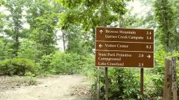 Trail sign showing Brown Mountain Garner Creek Campsite, Visitor Center, and State Park Primitive Campground Lake Crawford