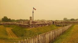 An eerie yellow, hazy sky surrounds the wooden fort. It makes it look strange.