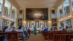 Photo of Rangers dressed in historic clothing in a large room with lots of people watching