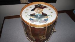 Drum featuring face and torso of man in white wig with black hat