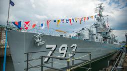 View of Cassin Young docked at a pier with nautical flags displayed.