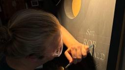 Michael Brache carving a gravestone with a chisel in dramatic low lighting