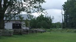 A building, wooden fence line, and green lawn.