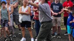 A park ranger gives a tour to a group of people on a trail.