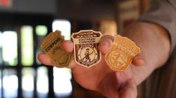 A hand holds out three junior ranger badges