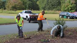 Three people in reflective vests work outdoors