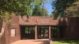 A dark-brown brick building--above the entrance is a sign: "Jockey Hollow Visitor Center"