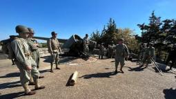 Group of men in uniform beside a historic cannon.