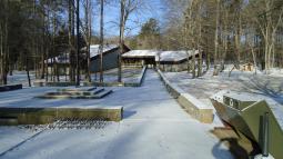 A dusting of snow covers walkway to visitor center in the woods.