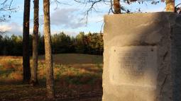 Photograph of a battlefield with a stone marker in the foreground.