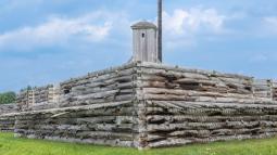 A vibrant flag waves over the walls of a wooden fort.