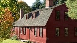 Red gambrel-roof farmhouse built in 1754 with center fireplace