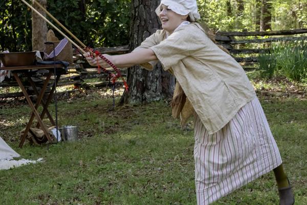 A young girl in colonial clothing plays the game of Graces