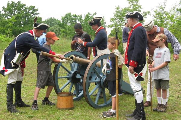 Patriot re-enactors show school age children how to fire a canon