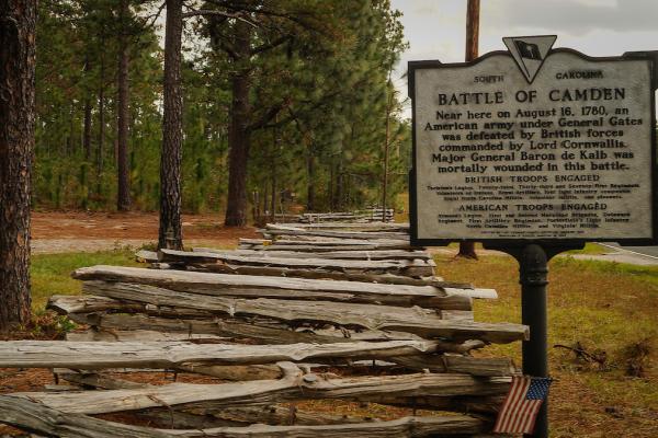 Image of a split rail fence along the side of a road with a historical marker sign reading Battle of Camede