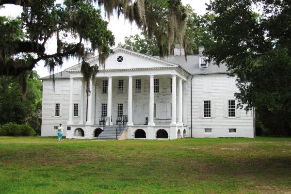 Image of the front of a large white house surrounded by trees