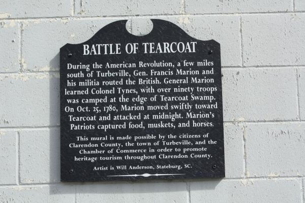 Black sign on a white brick wall with the title of Battle of Tearcoat