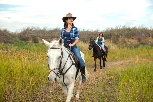 two women riding horseback in a field