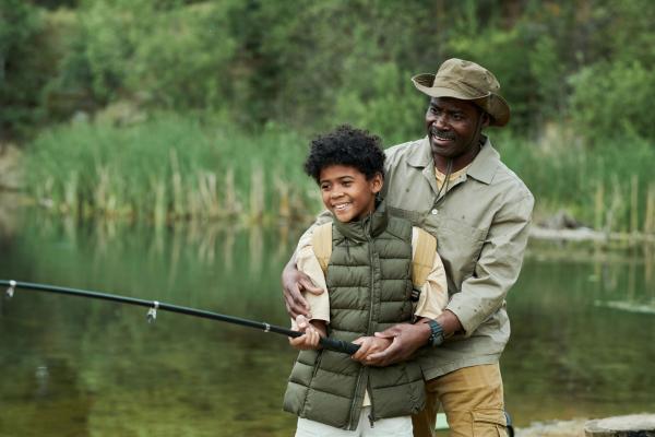 father and son fishing in a stream