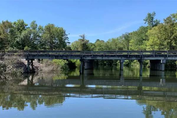 image of bridge over a river with trees and blue sky in the background