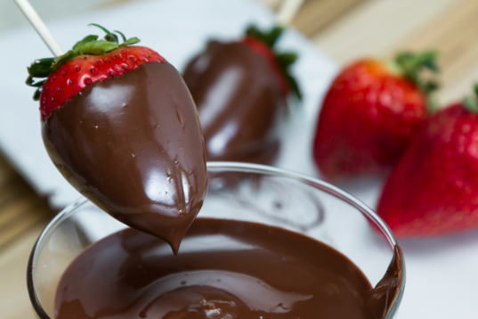 a photo of strawberries being dipped in chocolate