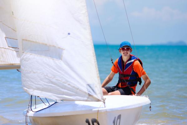 young person on a small sail boat on the water