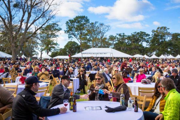 a photo of a crowd of people enjoying wine outside under tents