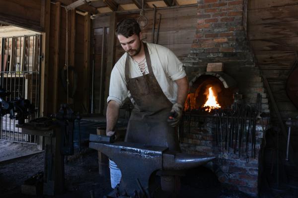 a man forges iron objects in front of an open fire