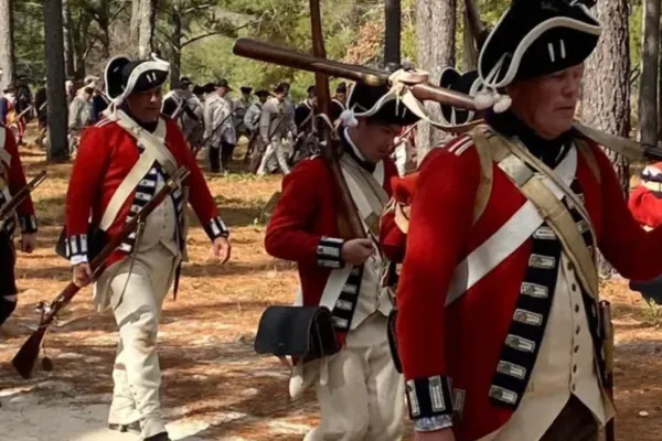 Reenactors march through the pines at the Camden Battlefield