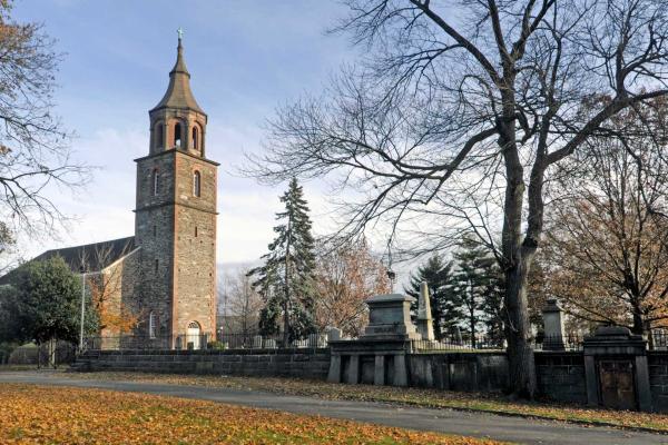Historic stone church tower surrounded by fall foliage