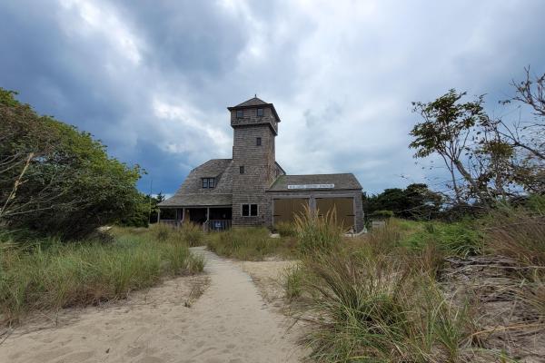 Historic shingle covered building among beach vegetation