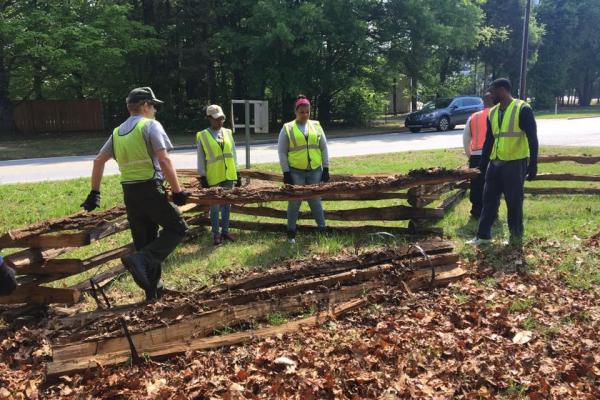 NPS staff and volunteers construct a split rail fence
